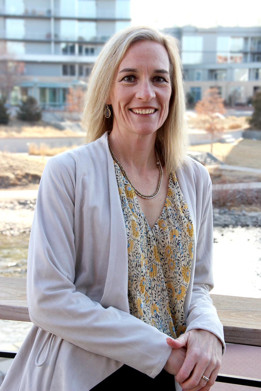 Dr. Rachael Van Pelt leaning on a railing outdoors in Colorado